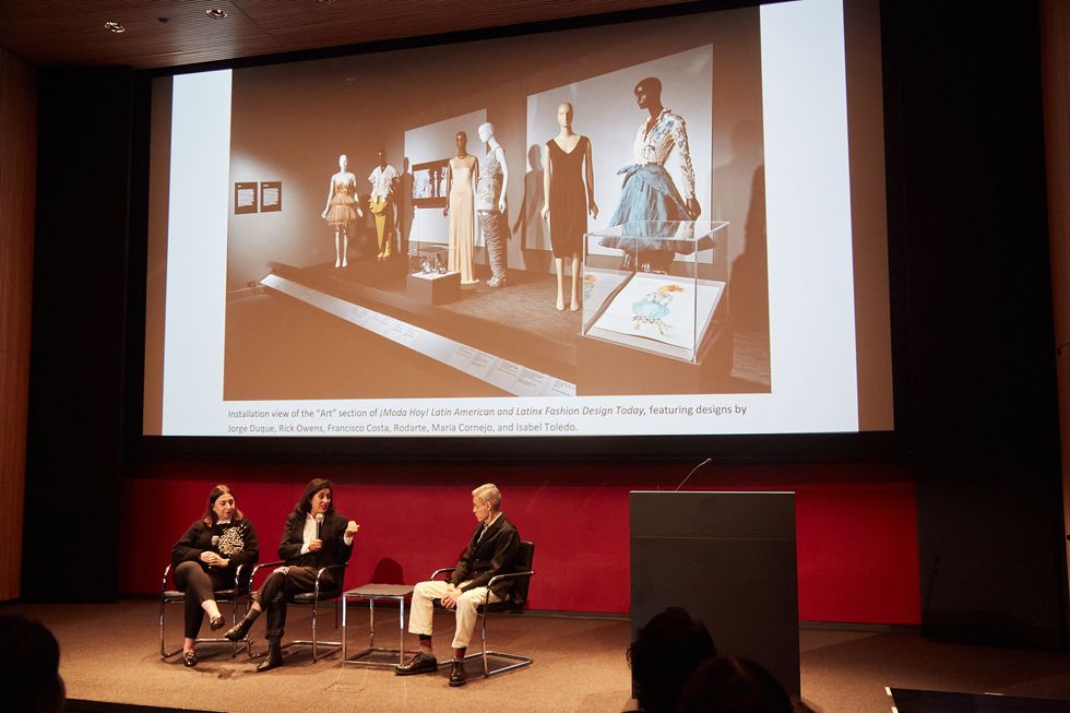 a group of people sitting on a stage in front of a projector screen